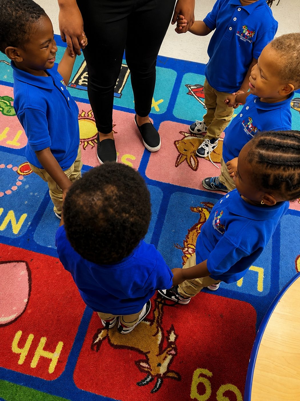 Children holding hands in a circle on the classroom rug
